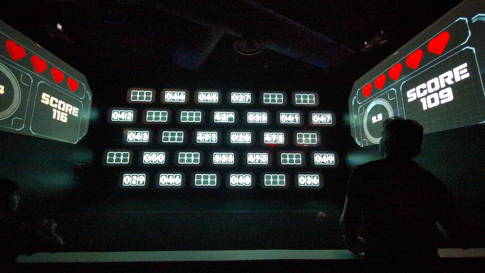 Player facing a wall of light-up targets with scores on screens in an Activate game room