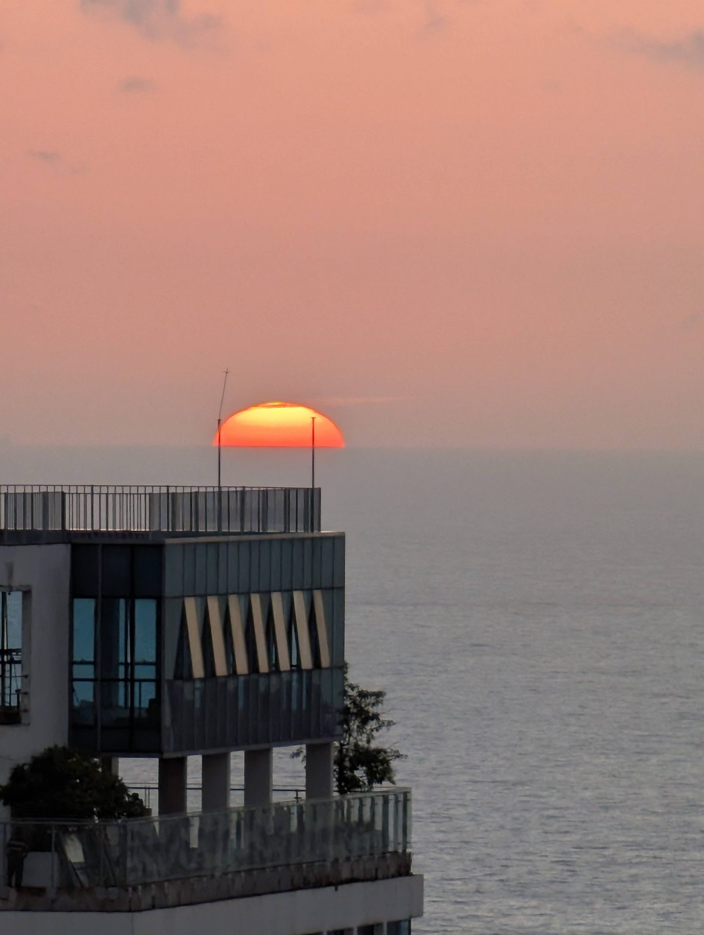 Sun setting into the Indian Ocean behind a Colombo apartment tower