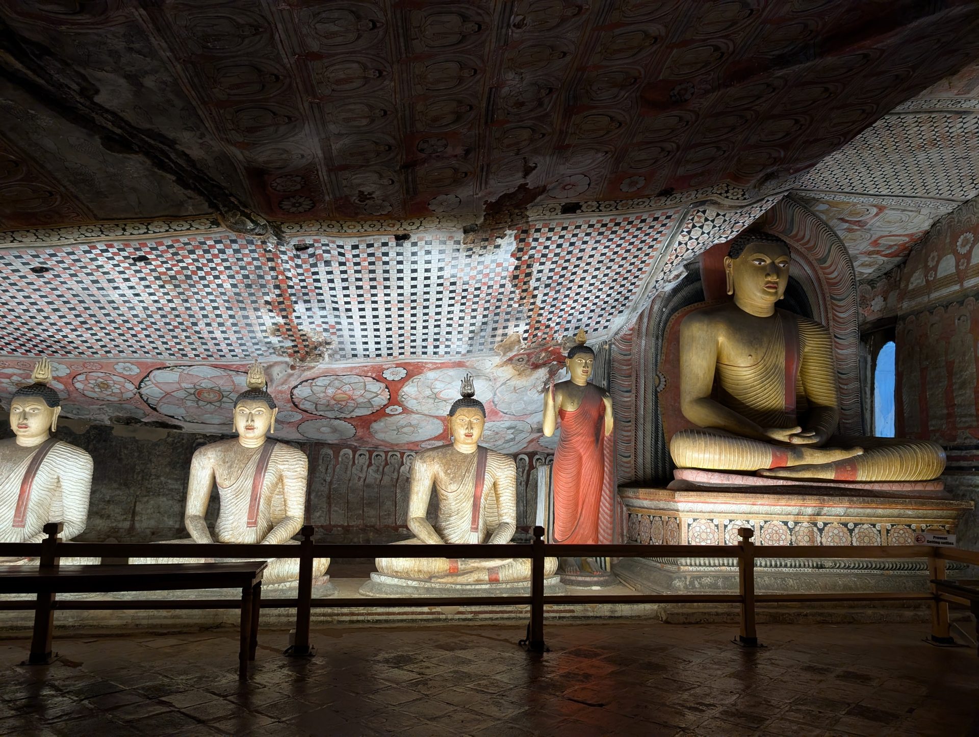 Seated Buddhas and painted walls inside Dambulla Cave Temple
