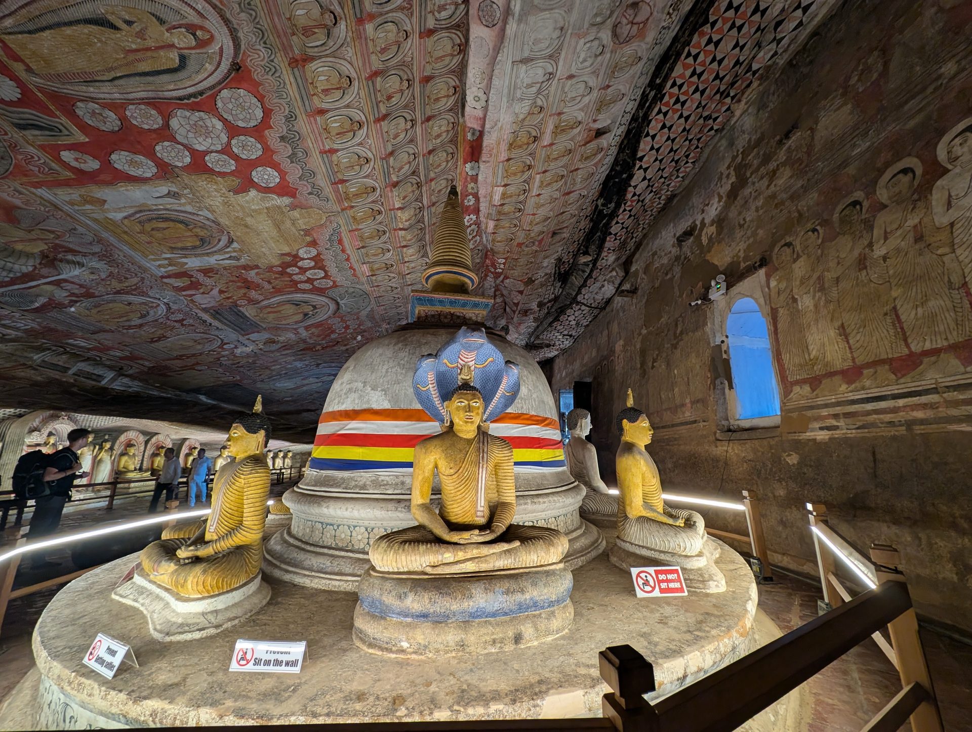 Small stupa surrounded by seated Buddhas inside a Dambulla cave