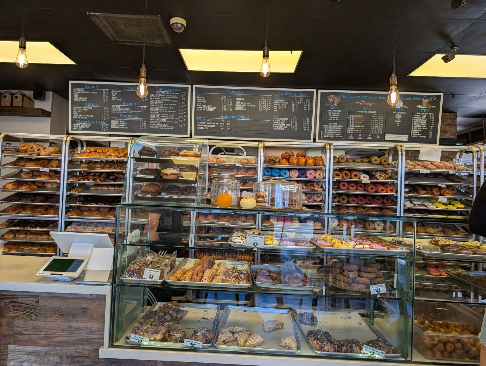 Donut cases and chalkboard menus inside The Donuttery Huntington Beach