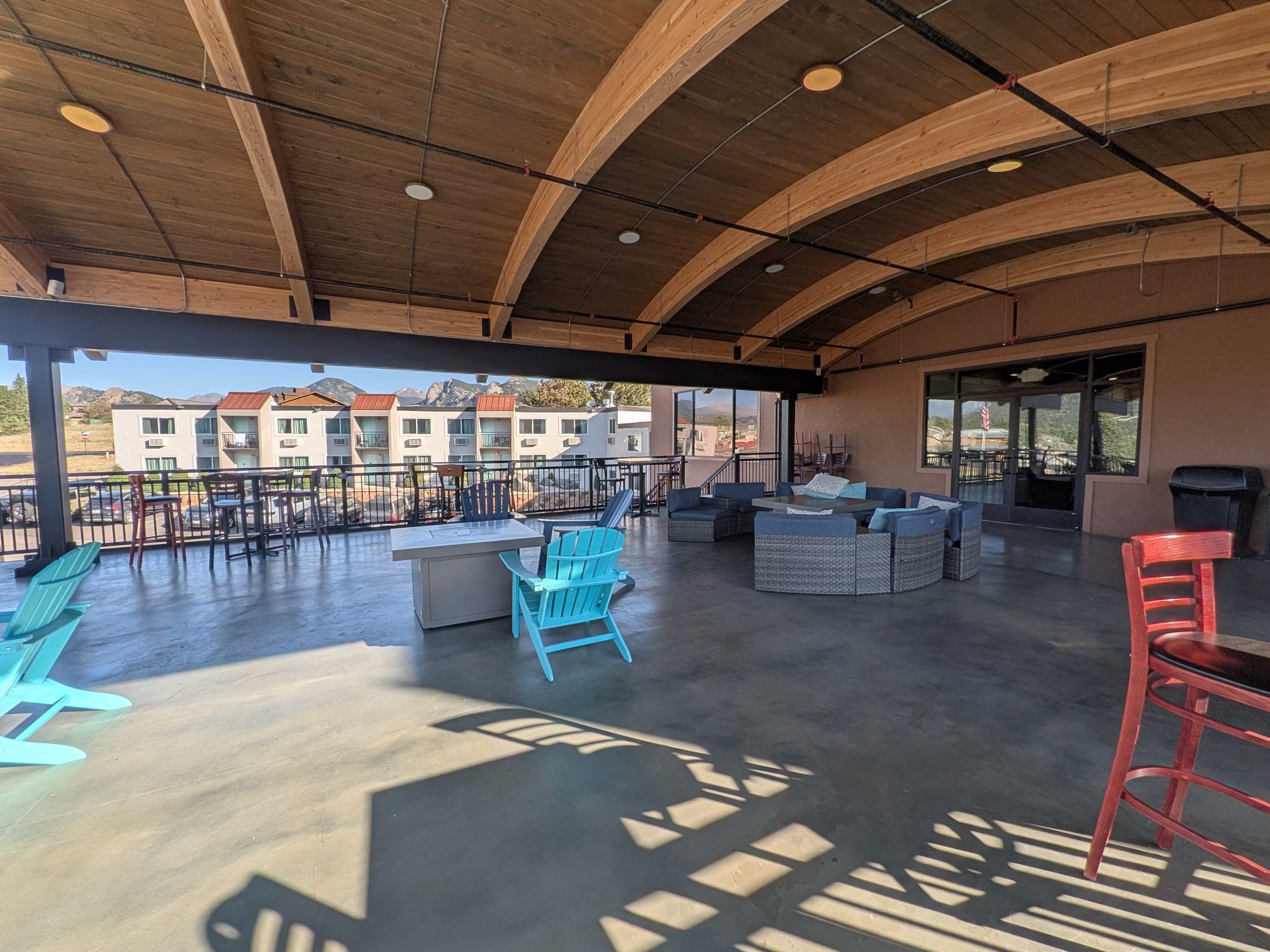 Covered second-floor patio at Expedition Lodge Estes Park with fire tables and Adirondack chairs