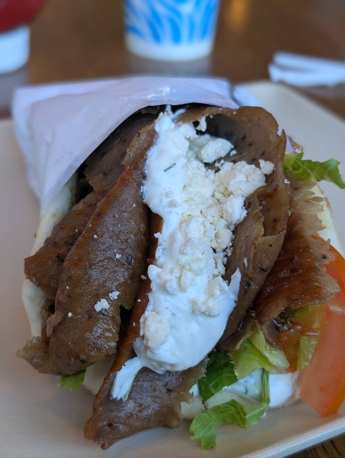 Close-up of a gyro pita with gyro meat, feta, tzatziki and tomato