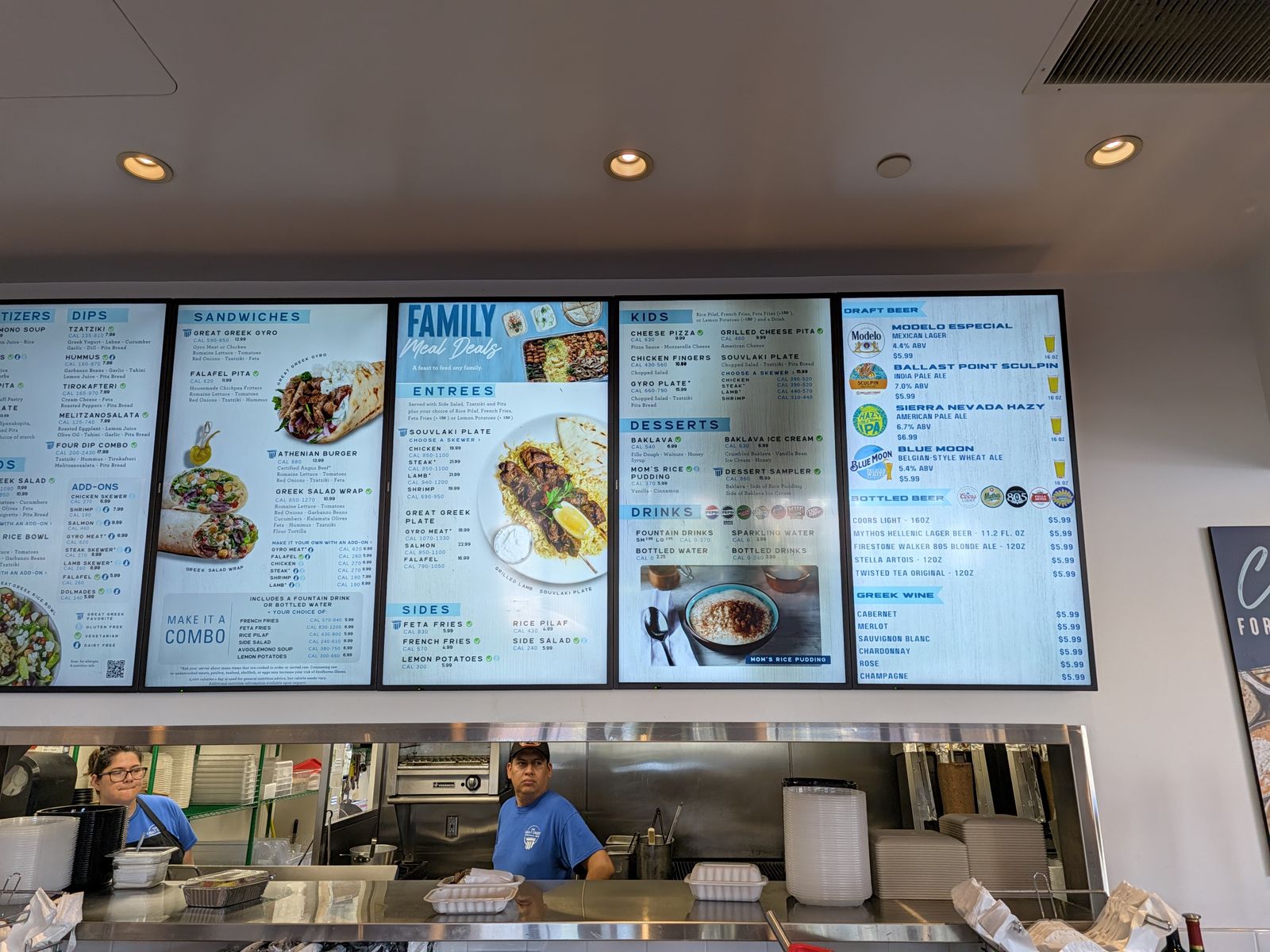 Menu boards showing sandwiches, entrees and family meal deals at The Great Greek