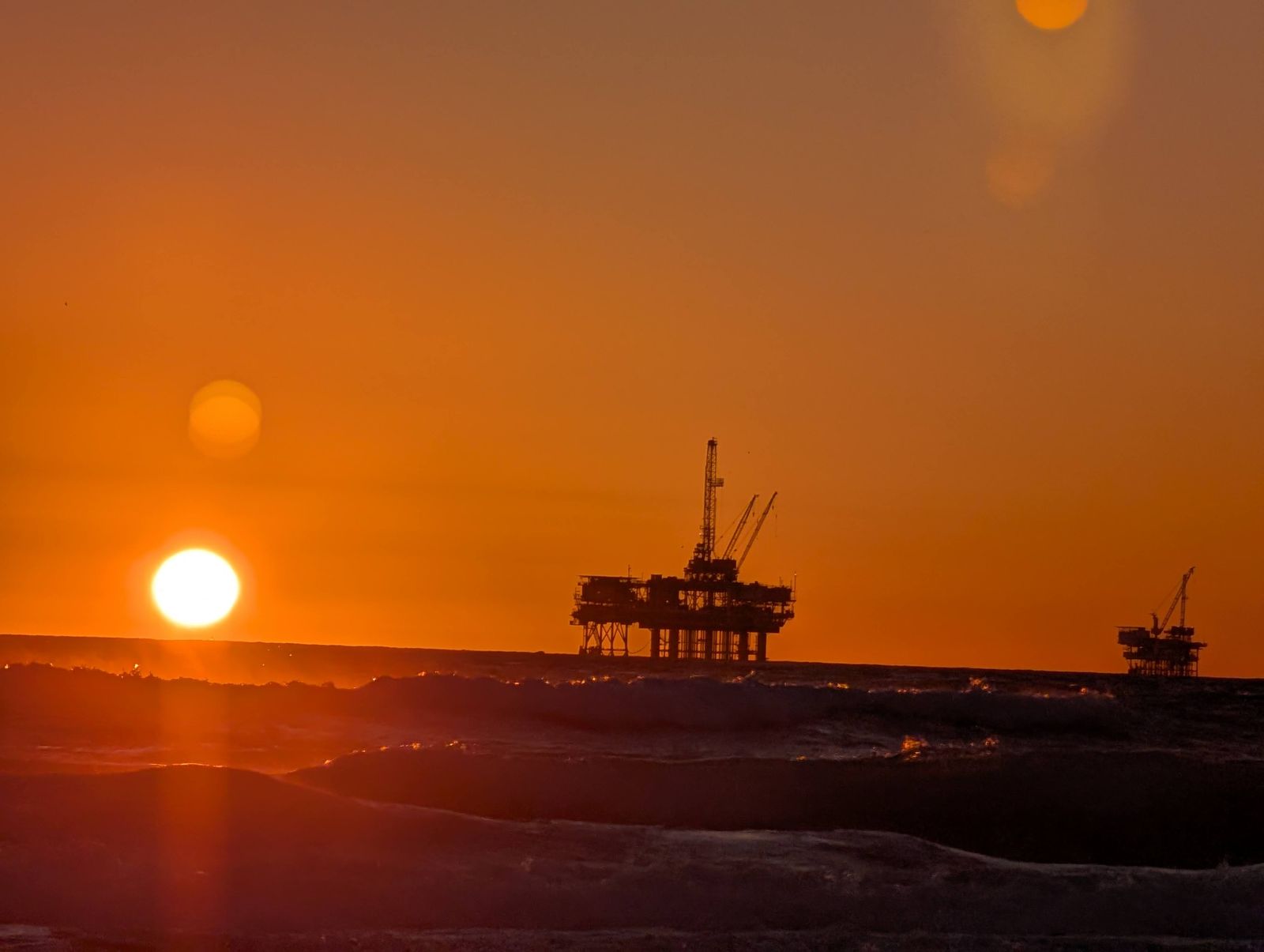 Sun setting next to an offshore oil platform off Huntington Beach