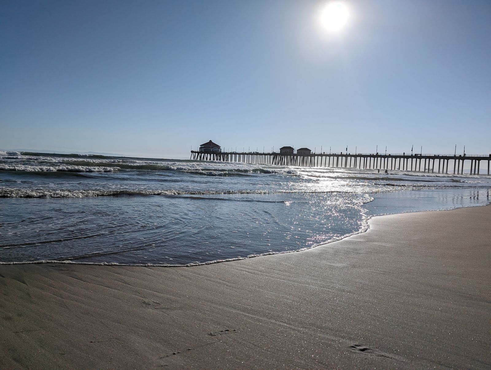 Waves rolling onto the shore beside Huntington Beach Pier