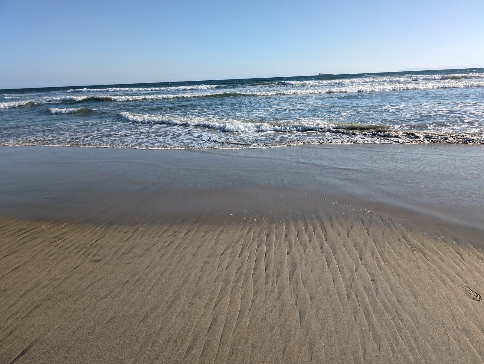 Ripples in wet sand at the water's edge in Huntington Beach