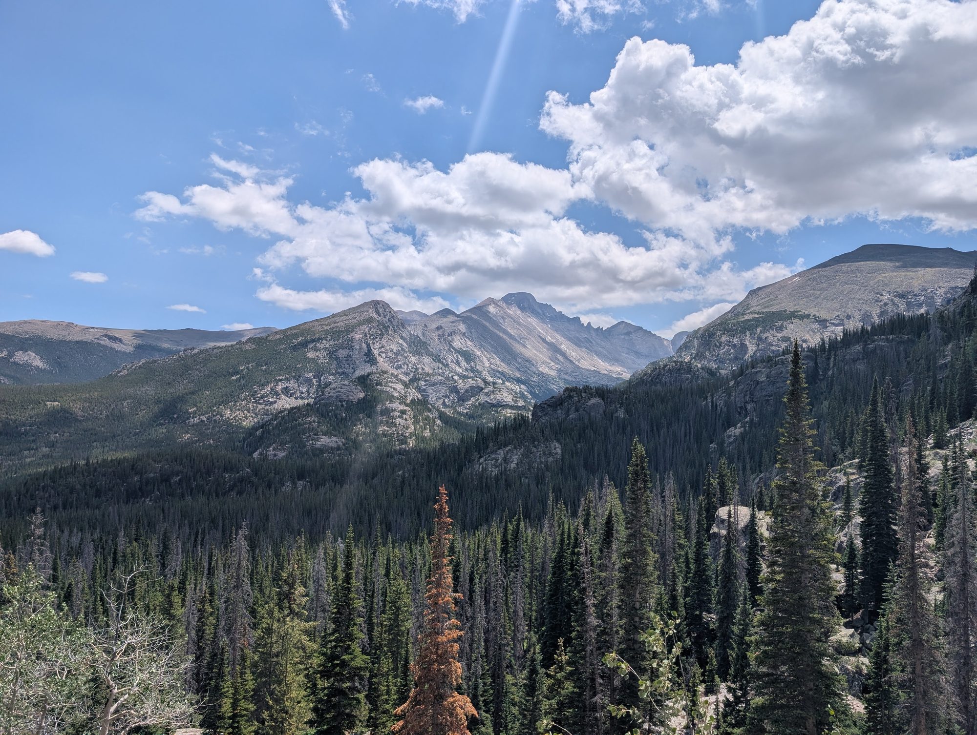 View of Longs Peak and forested valleys from the trail between Nymph Lake and Dream Lake