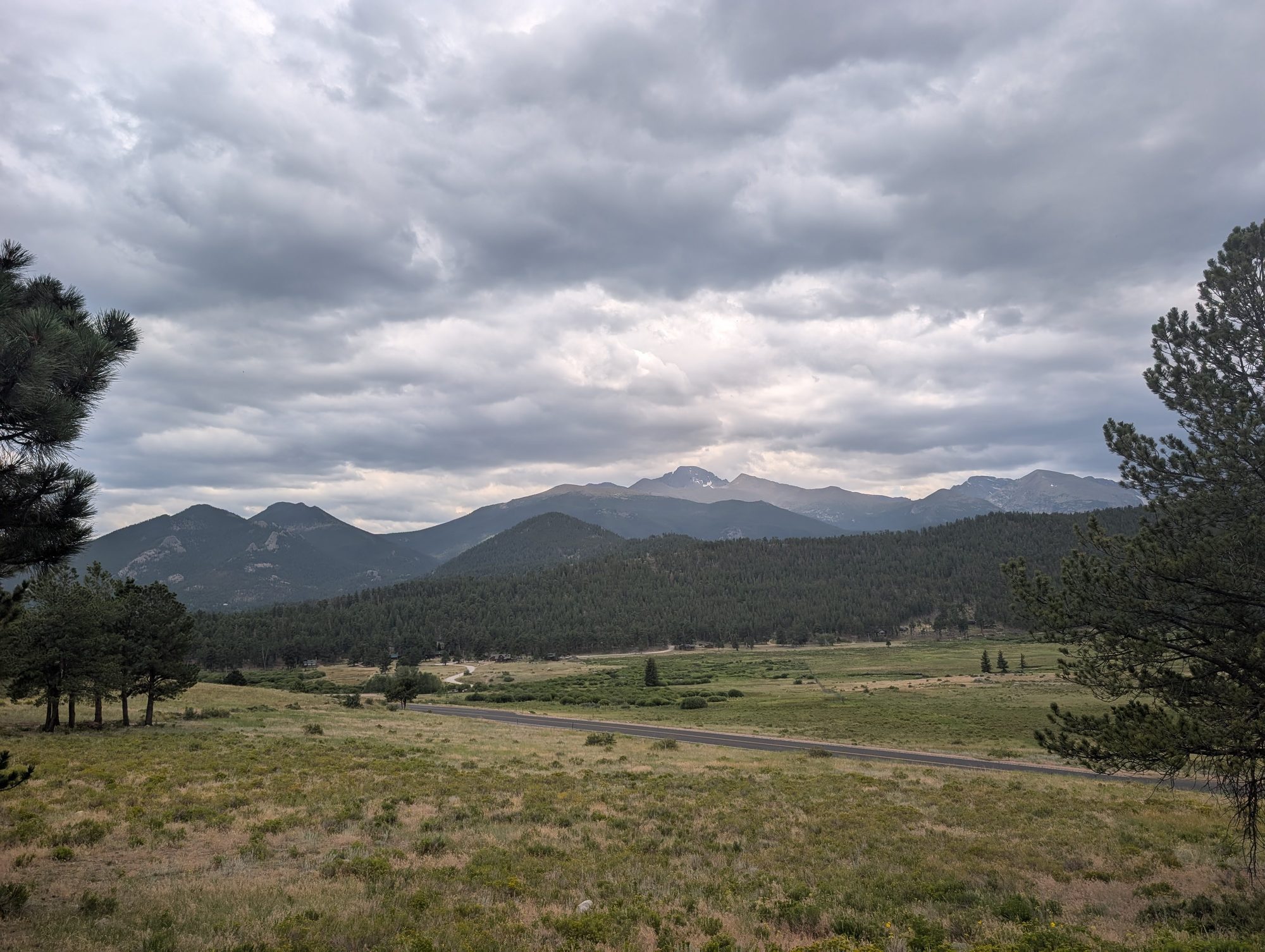 Moraine Park meadow with forested hills and mountains under clouds